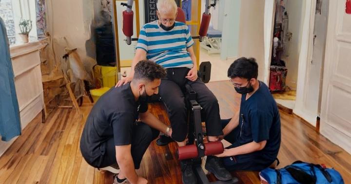 Two therapists supporting a patient in rehab